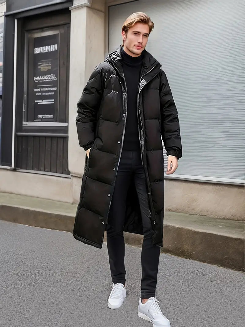  Ein Model trägt auf der Vorderseite eine schwarze, warme, lange gesteppte Winterjacke für Männer.