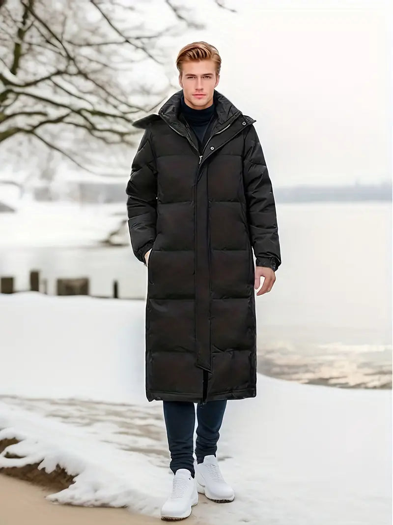  Ein Model trägt auf der Vorderseite eine schwarze, warme, lange gesteppte Winterjacke für Männer.