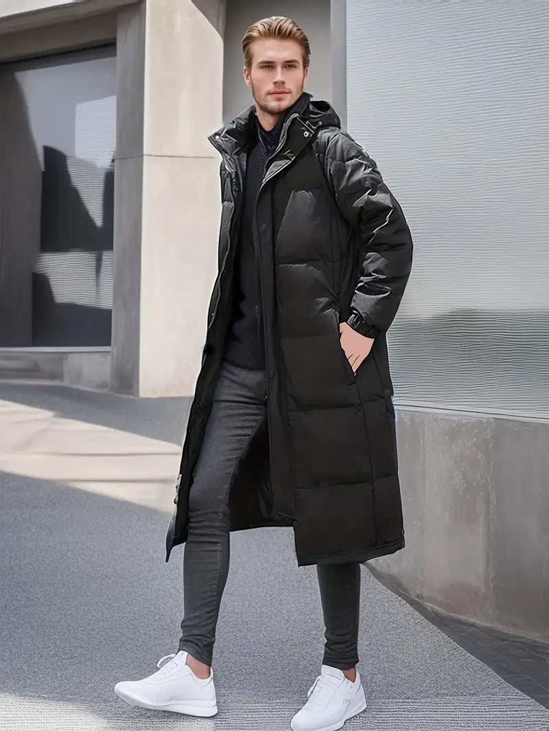  Ein Model trägt auf der Vorderseite eine schwarze, warme, lange gesteppte Winterjacke für Männer.